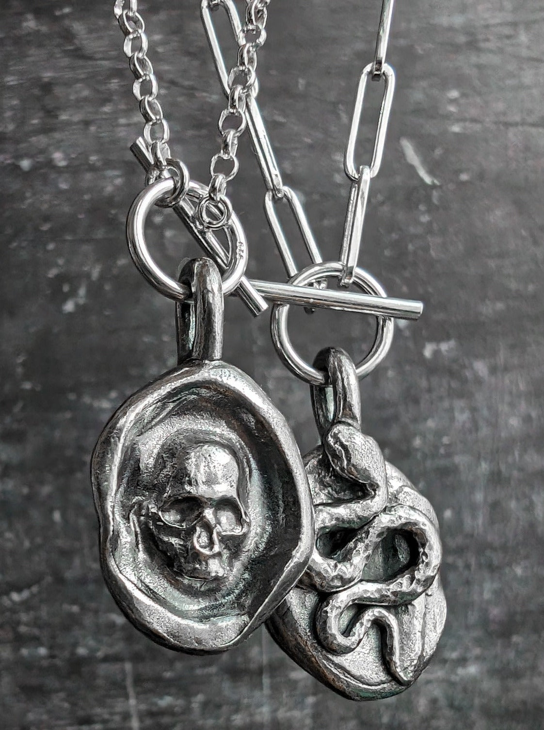 The two sides of a double sided snake and skull silver necklace