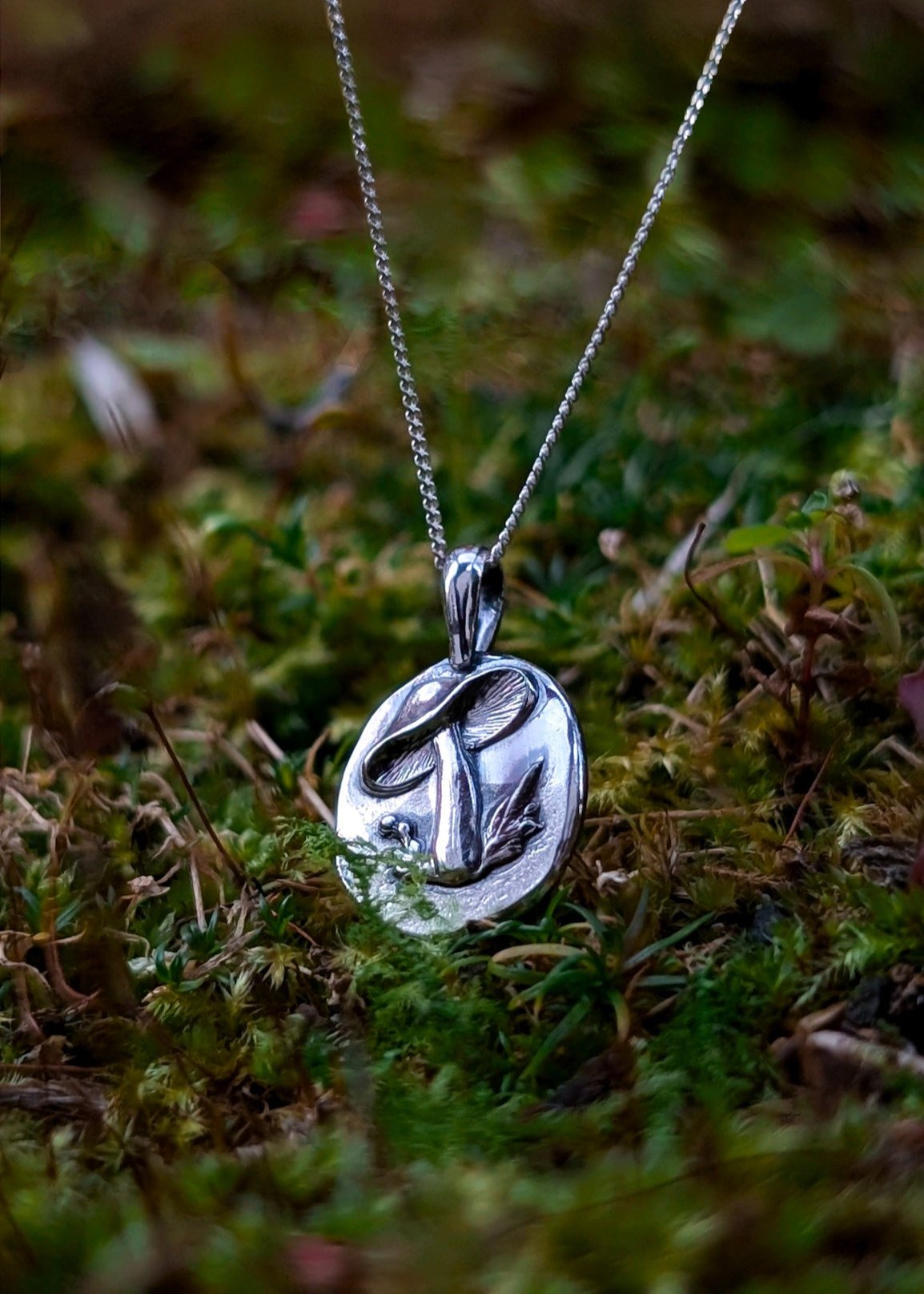 Sterling silver mushroom necklace photographed on an autumnal botanical background