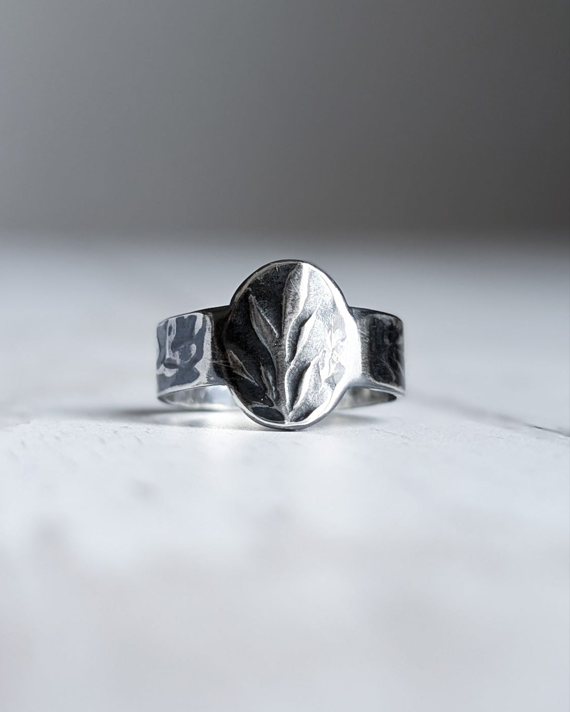 Darkened silver ring with botanical texture pattern