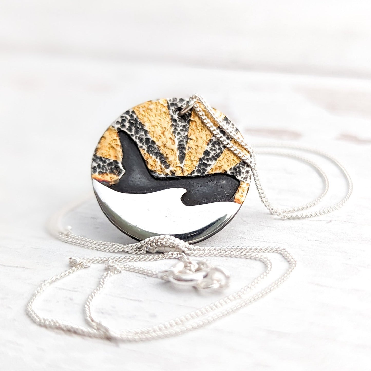 Gold sunburst orca pendant with silver wave