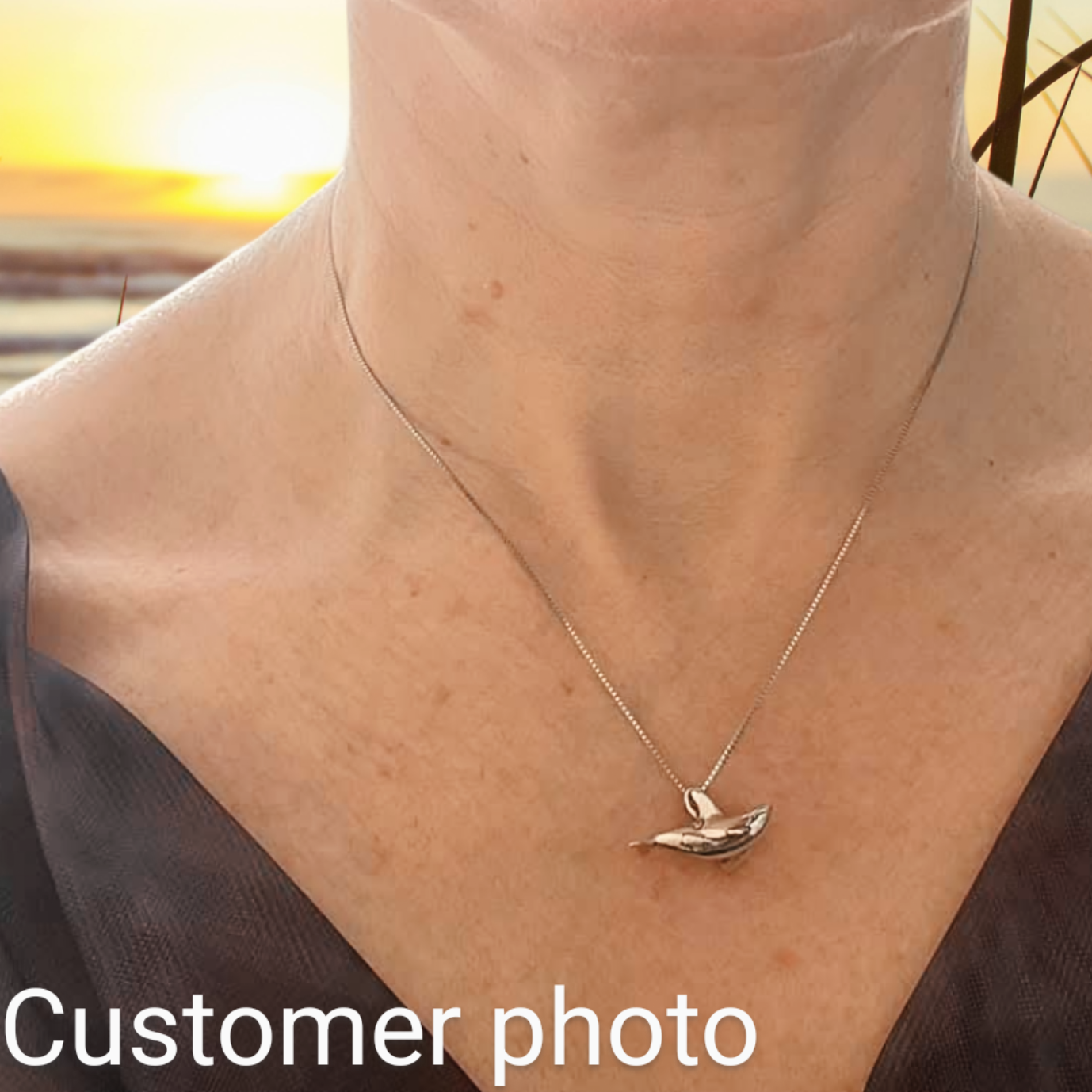 A customer-provided selfie image wearing the standard sized orca necklace, to show its petite size