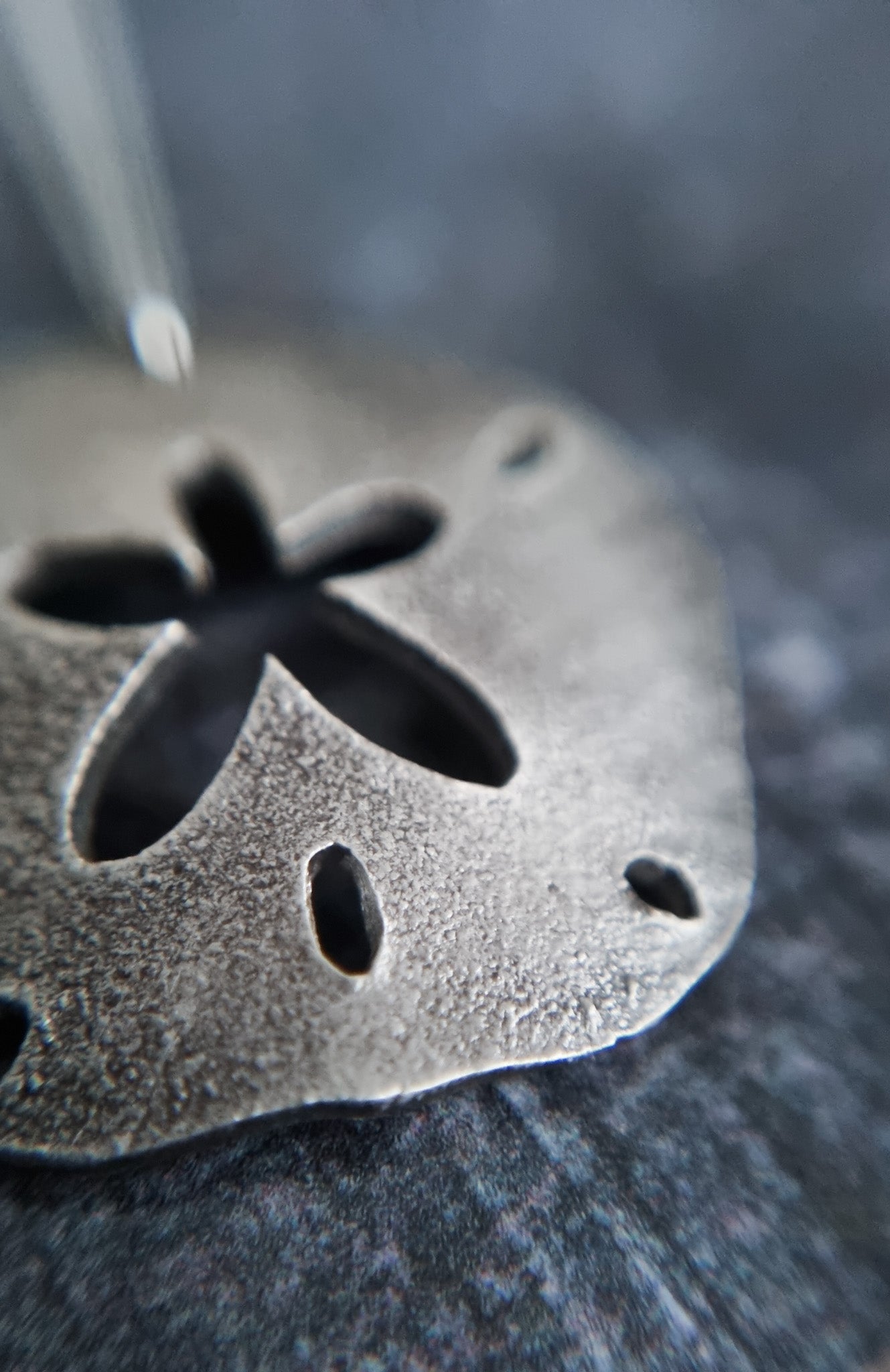 Texture detail on silver sand dollar pendant
