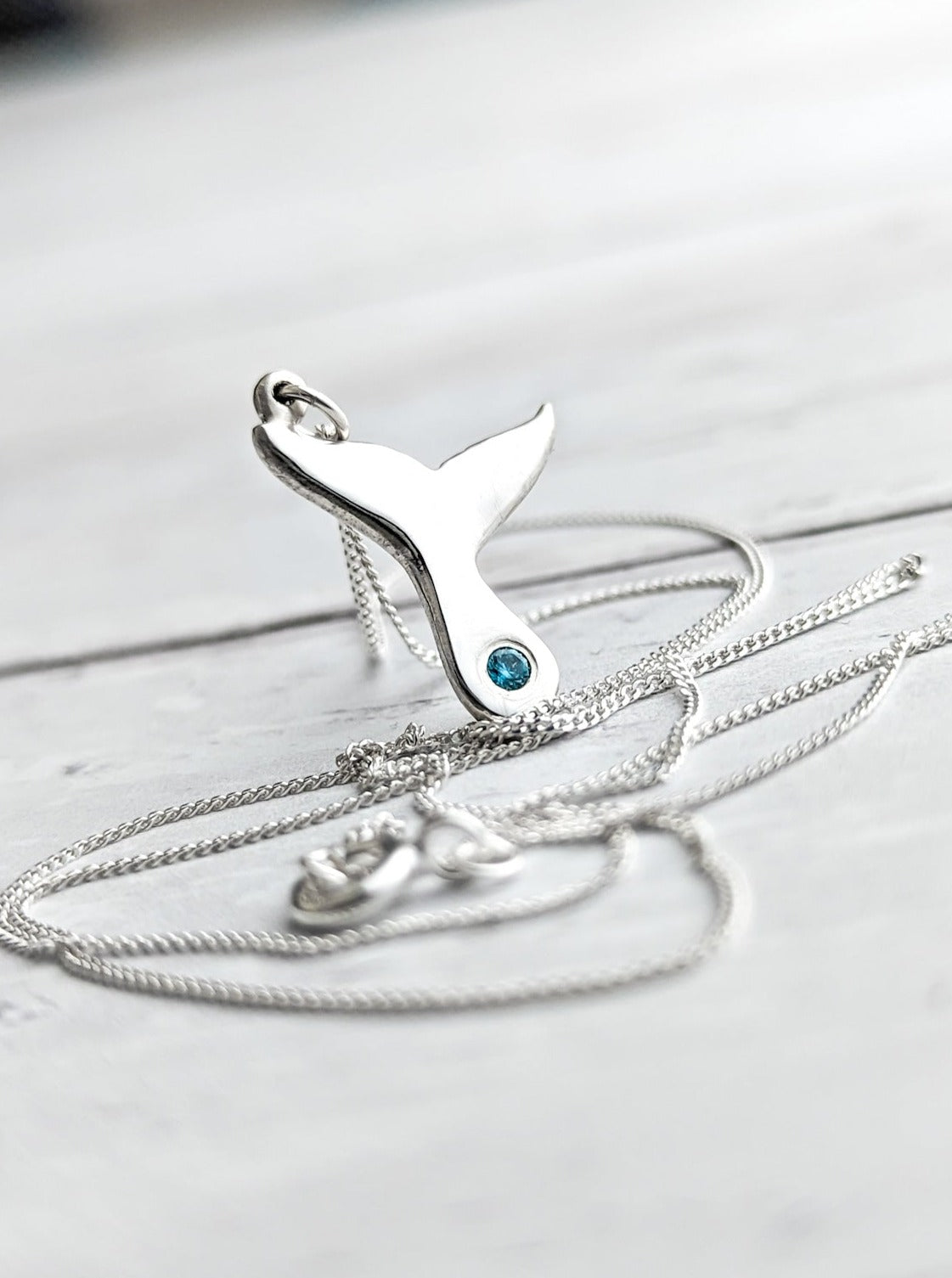 Whale tail necklace with vibrant blue birthstone