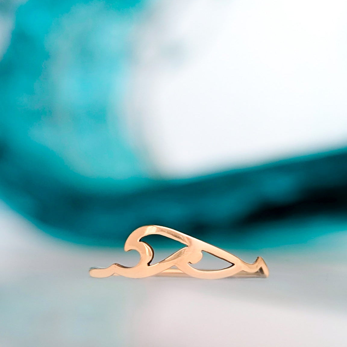 Celtic style wave ring pictured in front of an ocean blue background