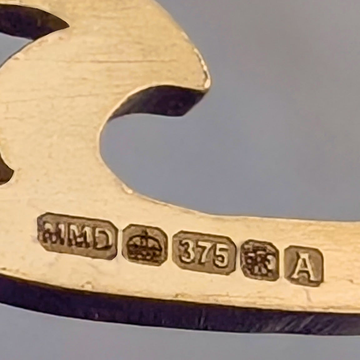 A very zoomed in image of the gold tribal wave ring, showing the Hallmark stamps that prove the gold purity and indicate when and where the article was made