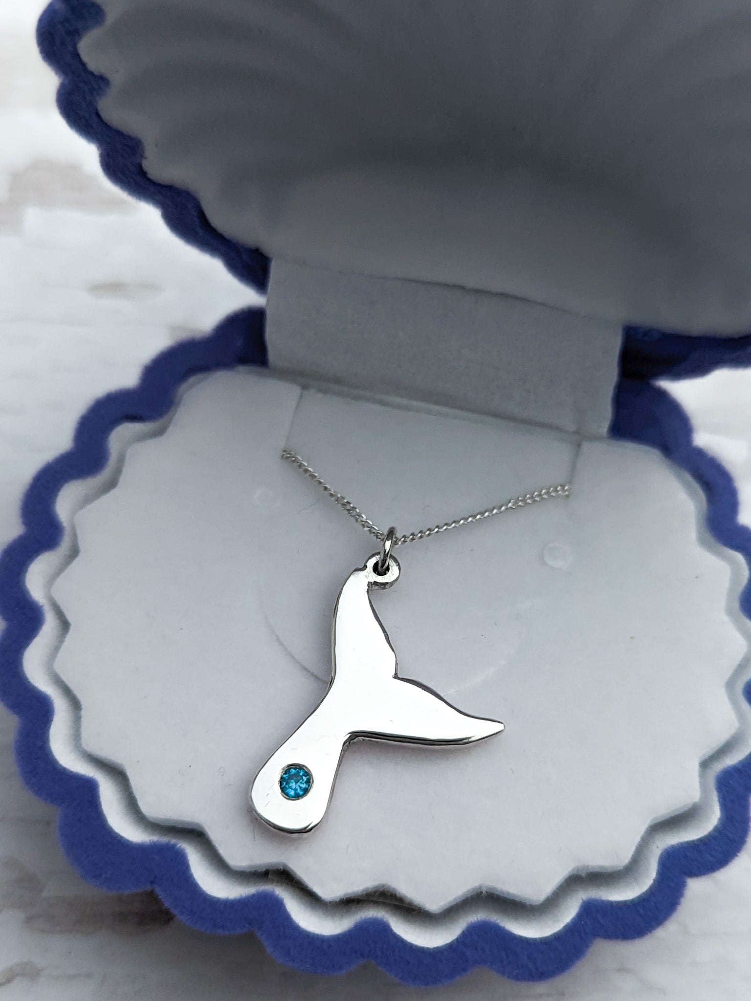 Whale tail necklace with blue flush set stone