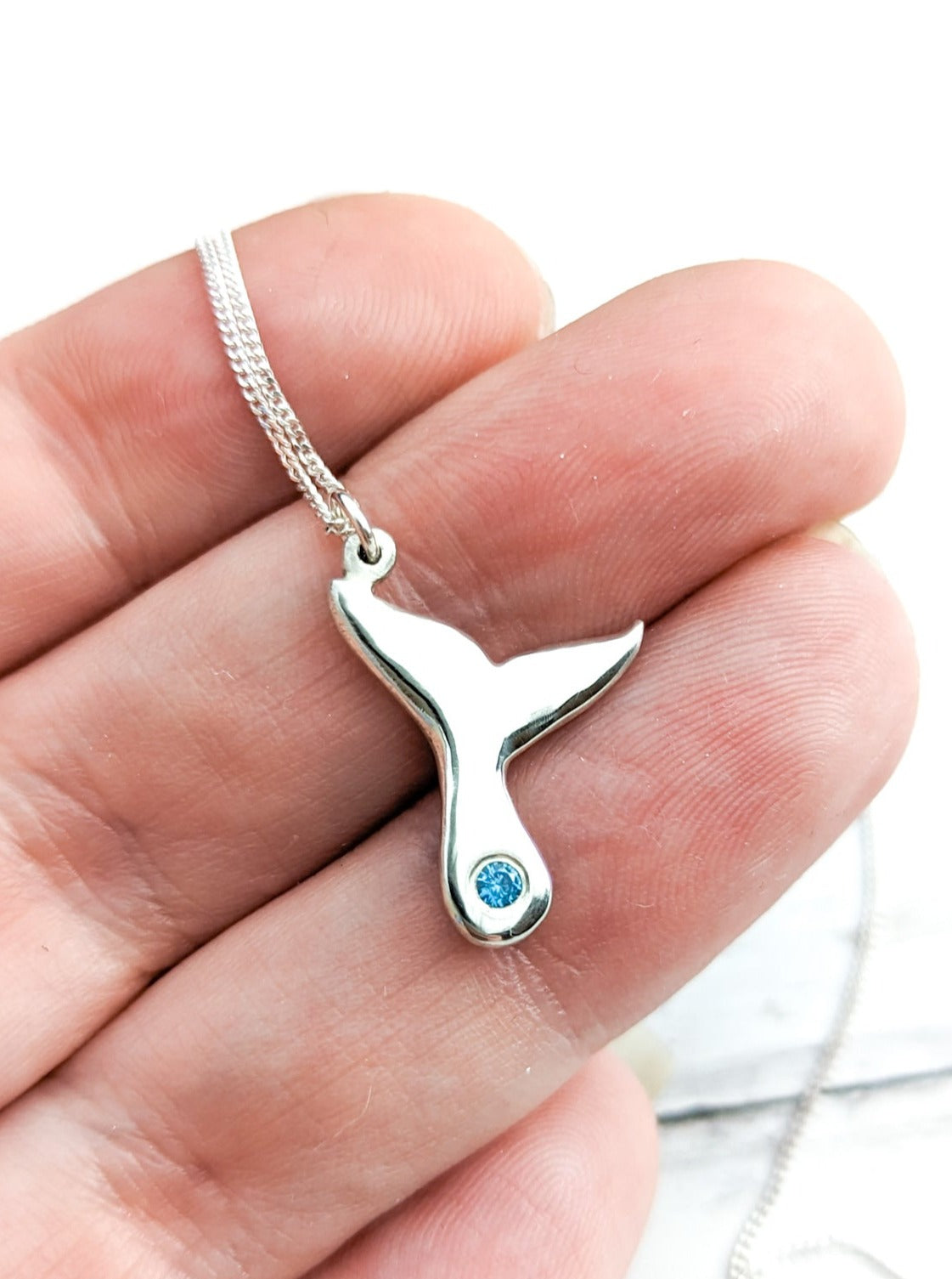 Silver whale fluke pendant with ocean blue stone