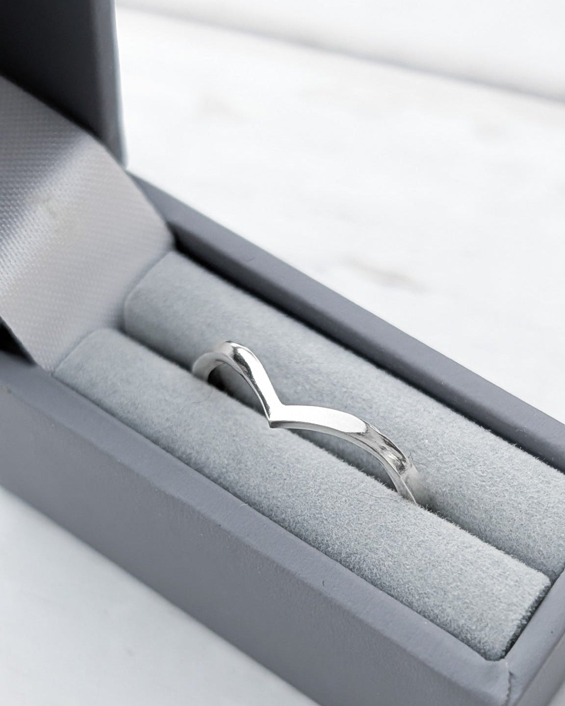 Silver chevron ring in a grey ring box on a white surface