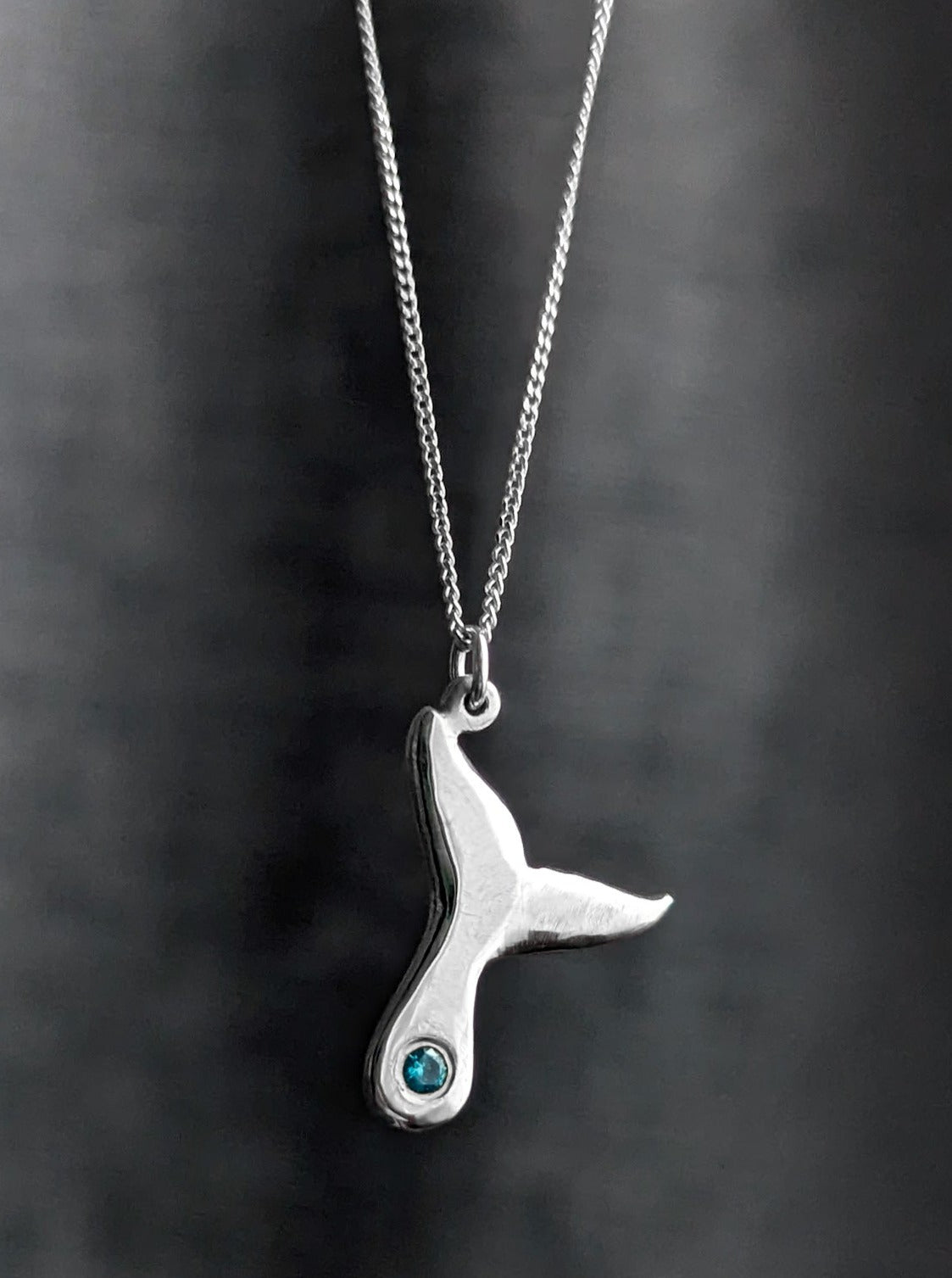 Shiny silver whale fluke pendant with blue birthstone